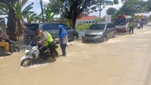 Jalan Tergenang Banjir, Polsek Benjeng Bantu Dorong Motor Yang Mogok