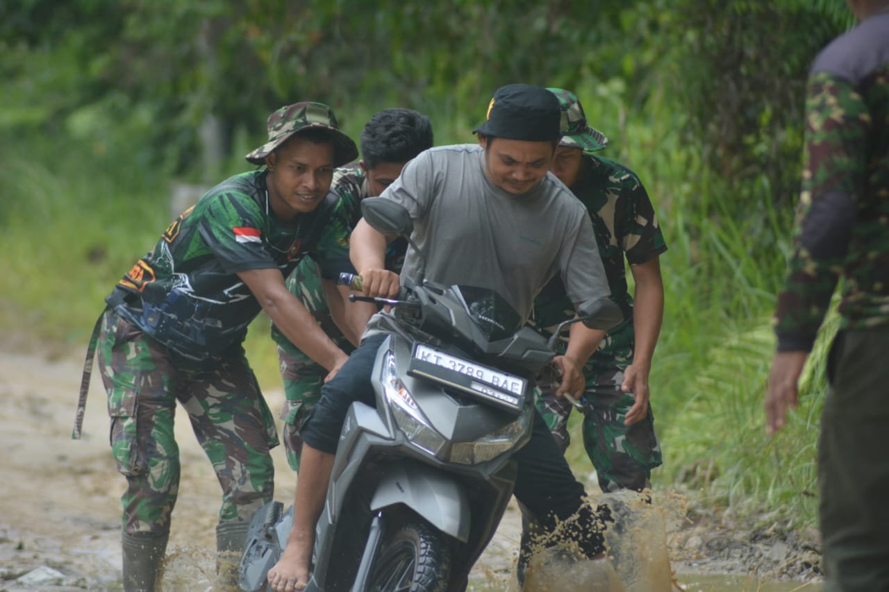 Personel Satgas TMMD ke 119 saat membantu masyarakat melewati genangan air yang cukup dalam diarean sekitar kegiatan semenisasi.( Dok : TMMD)