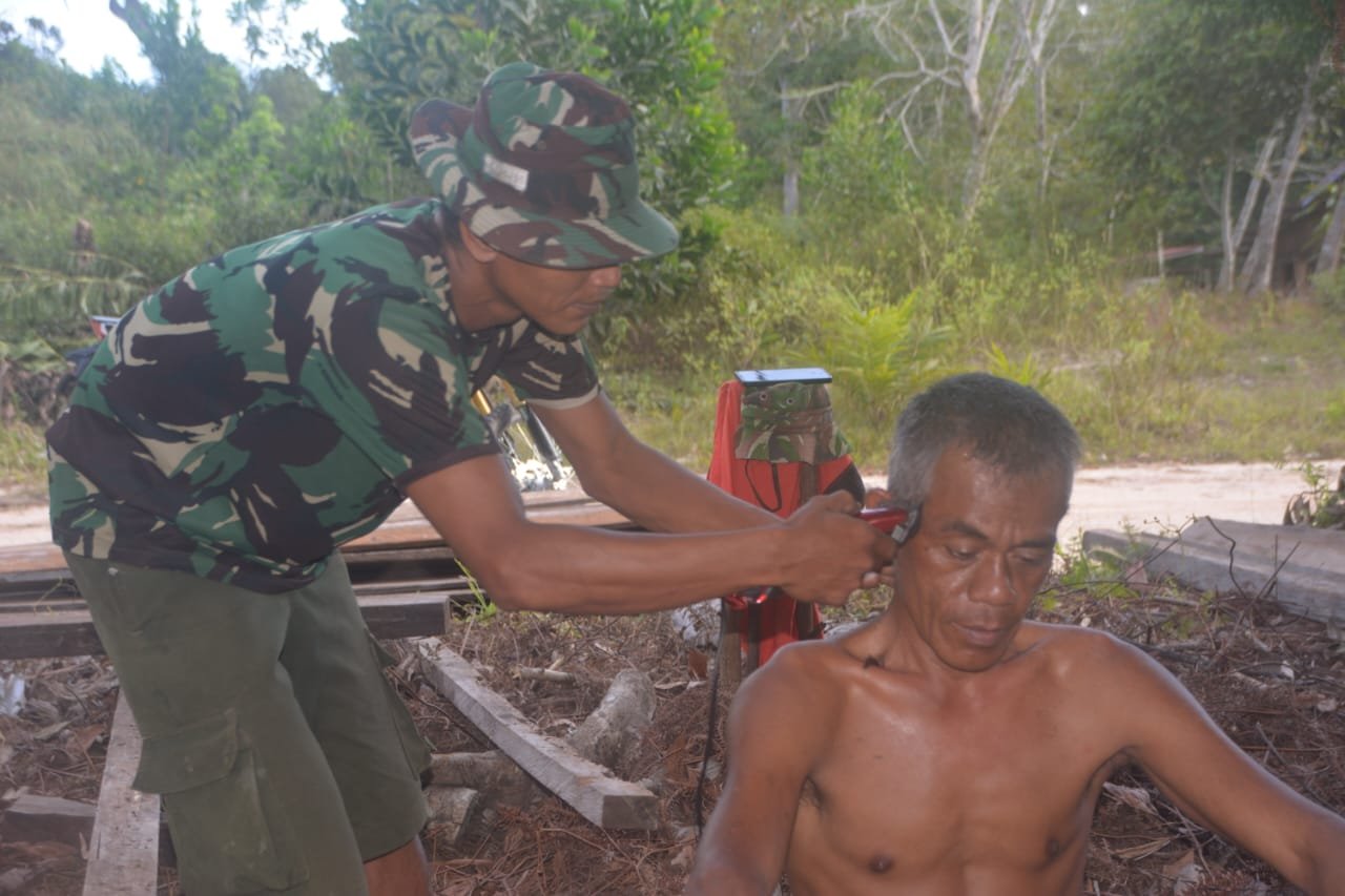 Serda Dianto saat mencukur rambut sesama anggota Satgas TMMD.( Dok TMMD)