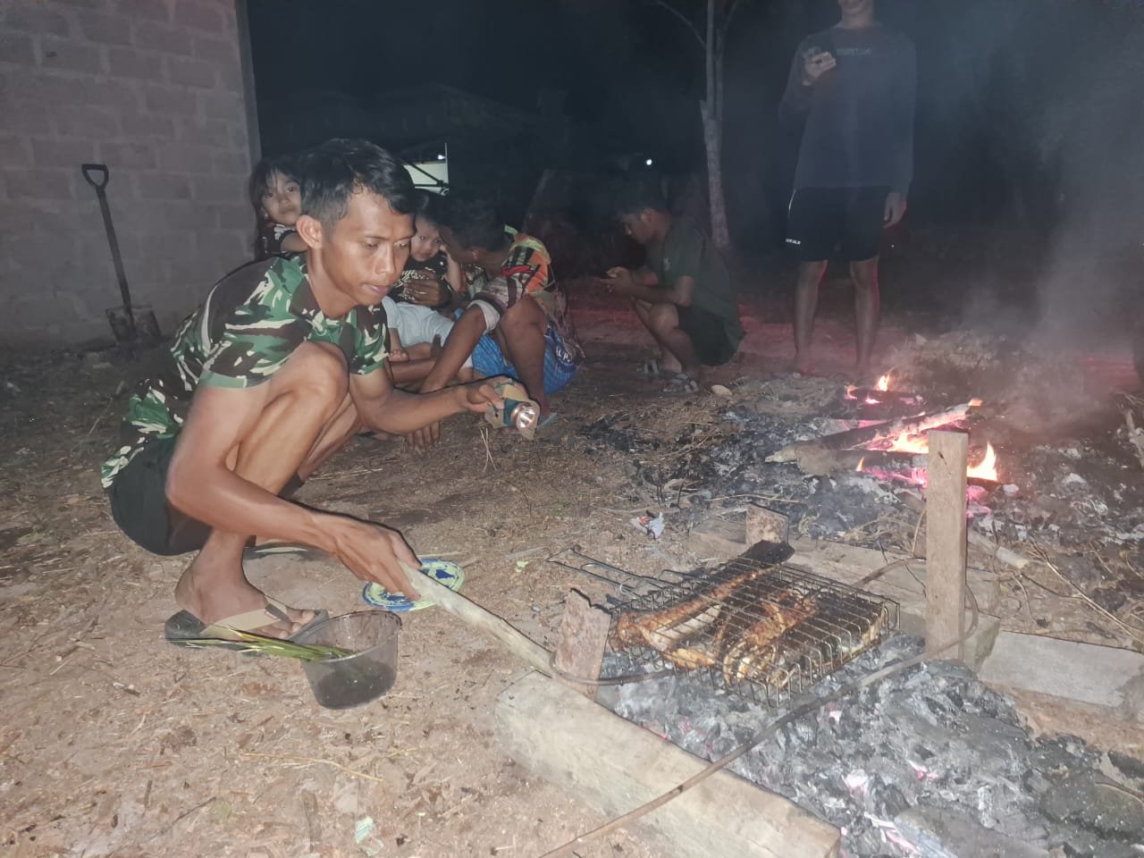 Bersama Orang Tua Asuh Anggota Satgas TMMD Bakar Ikan di Malam Hari